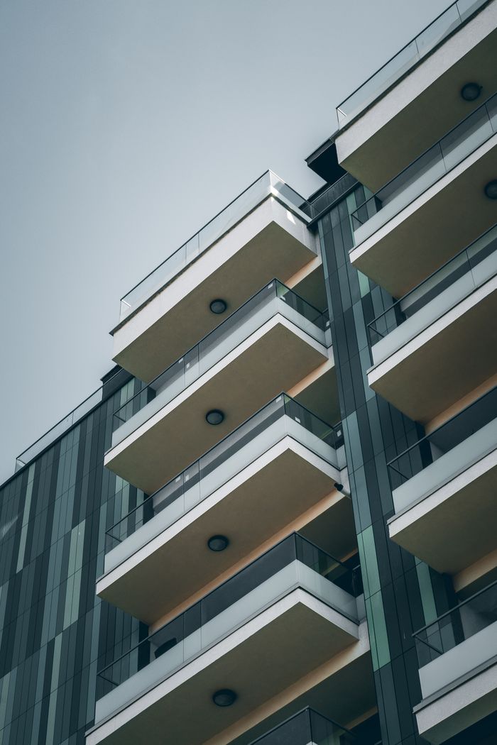 about-us From below facade of contemporary building with geometric pattern and glass balconies against cloudless blue sky
